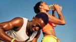 El hombre sonríe mientras la mujer a su lado da un trago de una botella con Liquid I.V. y agua durante un descanso en su actividad al aire libre.
